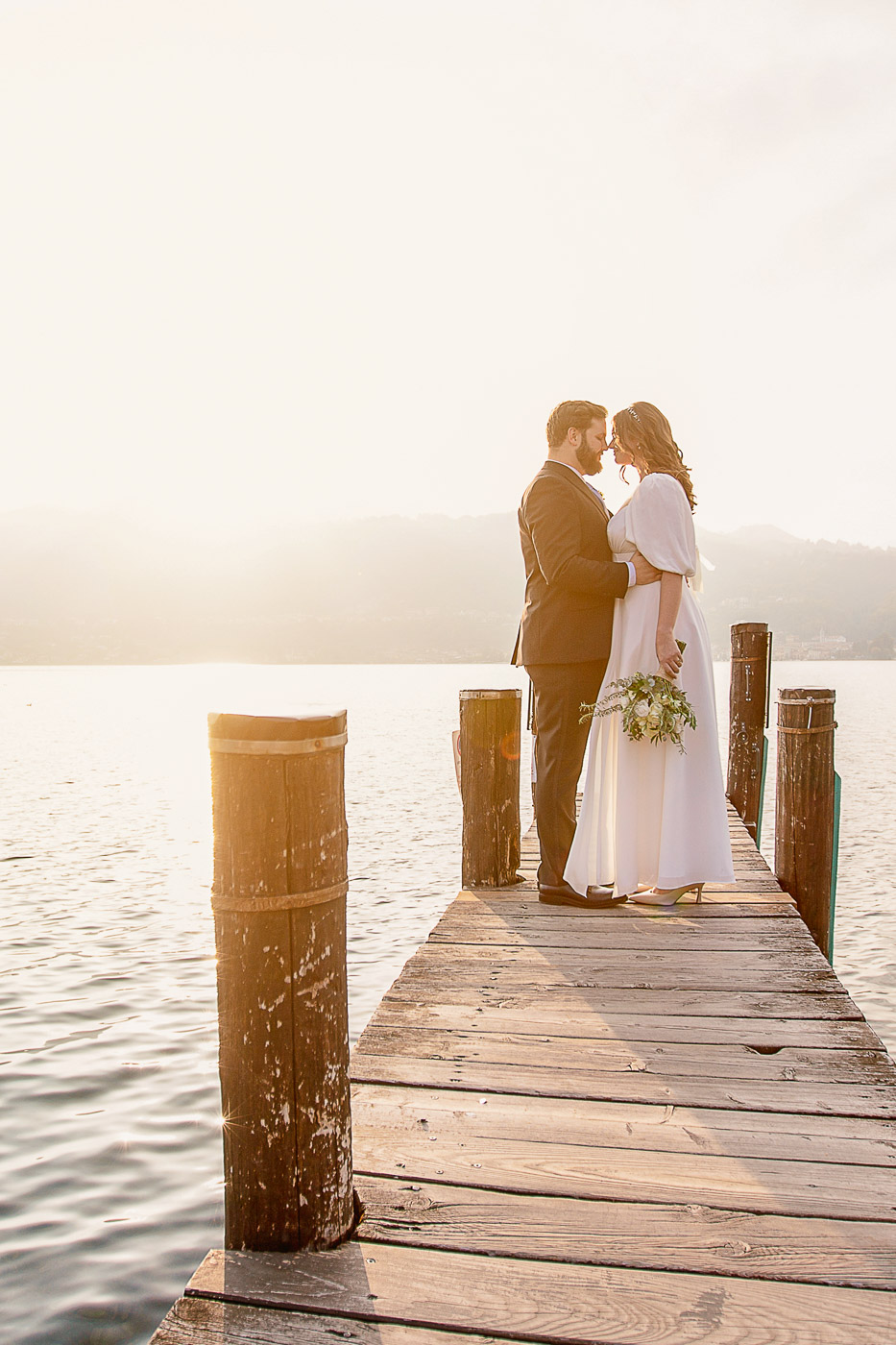 amazing sunset with bride and groom on a jetty by lake Orta