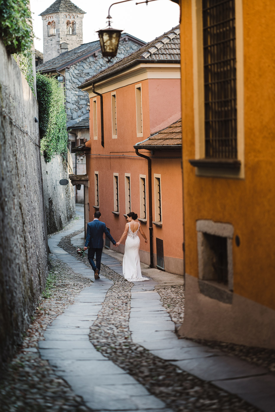 Bride and groom walking on narrow street of Orta san Giulio island