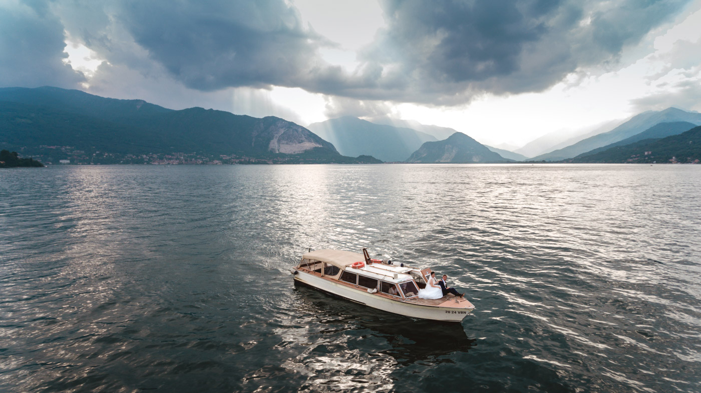 Lake Maggiore wedding photographer, drone shot with bride and groom on boat in the middle of Lake Maggiore and a stunning view of the lake and Alps